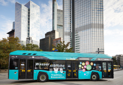 Brennstoffzellenbusse: Bus in türkis mit der Aufschrift "Wasserstöffche" steht vor Geschäftshochhäusern in Frankfurt am Main.
